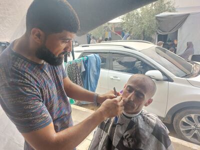 Bassam Qaffa, from Beit Lahia, who became displaced a month ago, has set up a makeshift barbershop to provide for his family. Mohamed Solaimane for The National