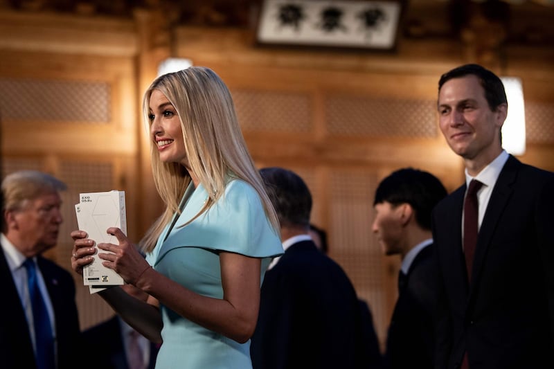 US Senior Advisor Jared Kushner, right,  watches as his wife and Advisor to the US President Ivanka Trump, left, holds copies of K-pop band Exo's album 'Love Shot', as US President Donald Trump, background left, waits for a working dinner with South Korea's President Moon Jae-in at the tea house on the grounds of the presidential Blue House in Seoul. AFP