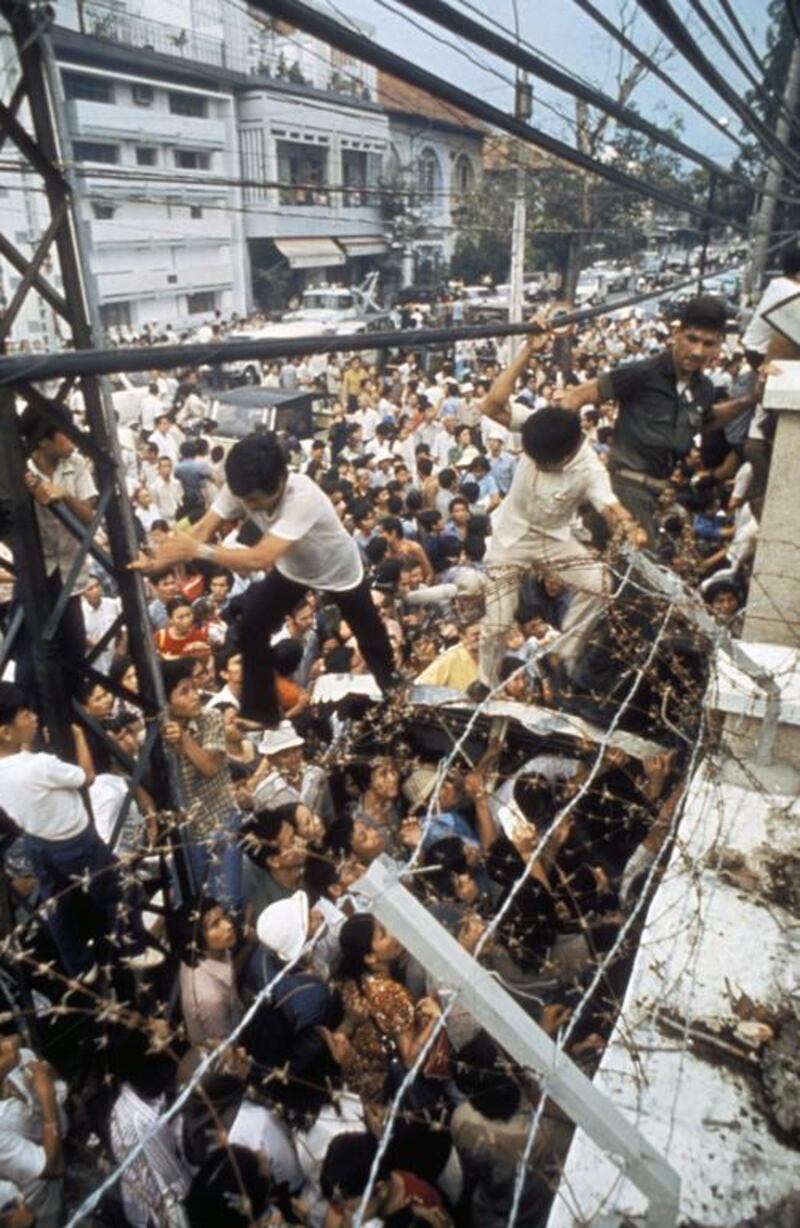 An American Marine guard dislodges two Vietnamese men trying to climb over barbed-wire wall into American Embassy to escape advancing North Vietnamese troops on the last day of the US involvement in the Vietnam War, in April 1975. Image by Nik Wheeler / Corbis