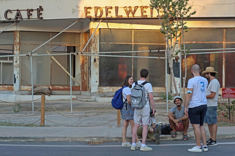 Visitors sit in front of an abandoned coffee shop in Varosha.