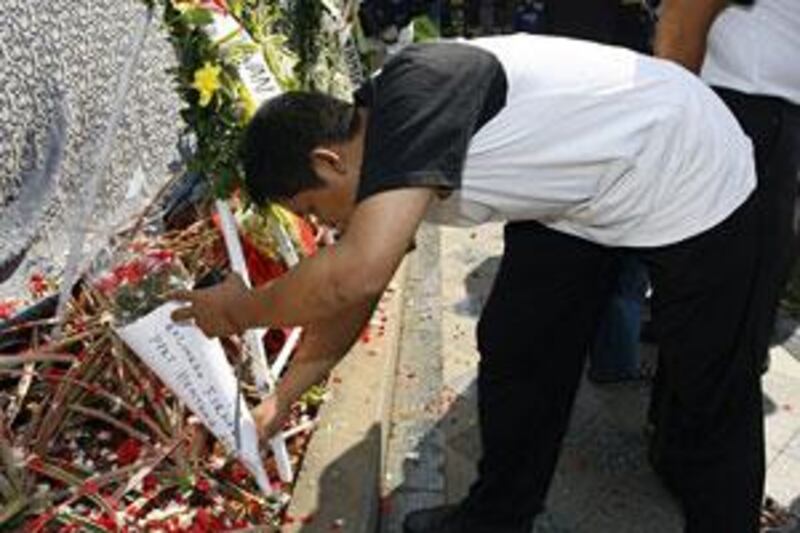 A mourner lays flowers at a makeshift shrine outside the Ritz Carlton Hotel bombing site in Jakarta.