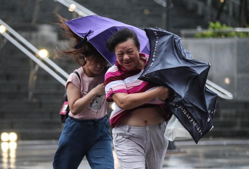People struggle with the wind as they cross the street under the rain as Typhoon Mitag approaches northern Taiwan, in Keelung.  EPA