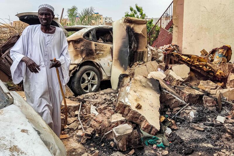 A man inspects the damage as he walks near a destroyed building and car in the Azhari district of Khartoum on June 6. AFP