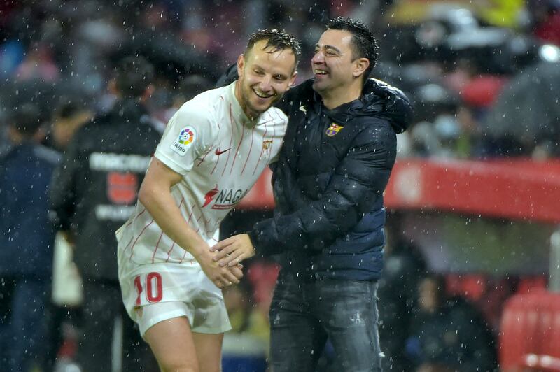 Xavi helps Sevilla's Croatian midfielder Ivan Rakitic, his former teammate, to stand up. AFP