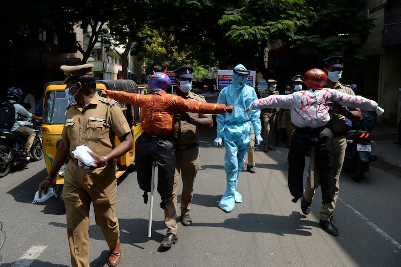Policemen hold effigys of demons representing the Covid-19 Coronavirus during an awareness campaign along a street in Chennai as India surged past 13 million coronavirus cases. AFP