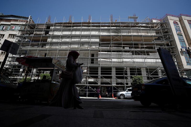 A Palestinian woman walks past the construction site of an office building, in Ramallah in the Israeli-occupied West Bank. Reuters