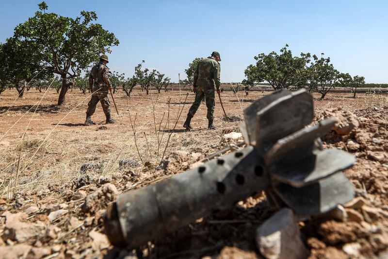 Syrian army soldiers use detectors to find and clear landmines in a field at a pistachio orchard in the village of Maan, north of Hama in west-central Syria.  AFP