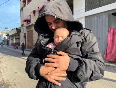 A Palestinian man holds his displaced niece in Rafah, the southern Gaza Strip. Reuters 