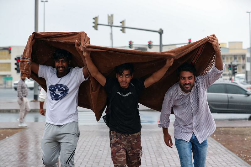 Residents take impromptu shelter from the rain in Al Quoz, Dubai. Chris Whiteoak / The National