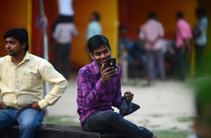 In this photograph taken on October 14, 2018, an Indian man uses a smartphone for a video call at a park in Allahabad. (Photo by SANJAY KANOJIA / AFP)