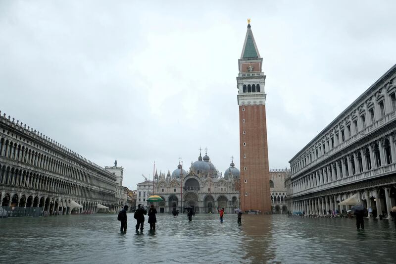 FILE PHOTO: People wade through a flooded St. Mark's Square during a period of seasonal high water in Venice, Italy, November 24, 2019. REUTERS/Manuel Silvestri/File Photo