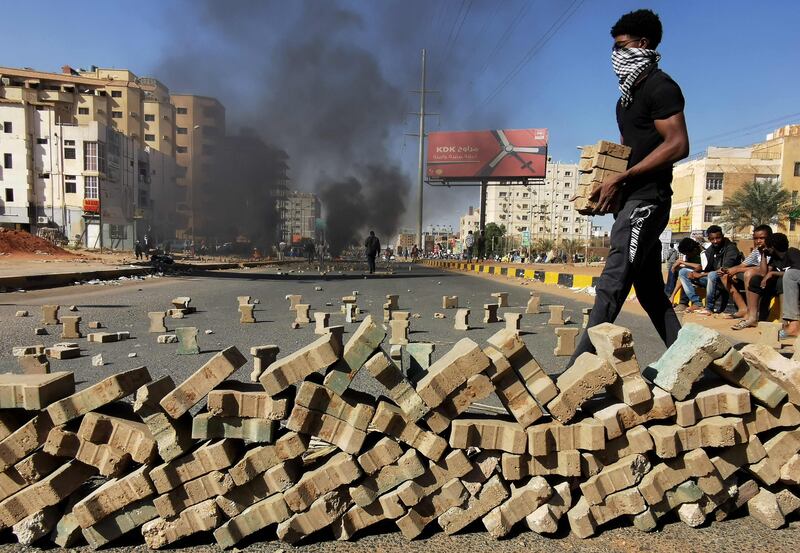 Protesters use bricks to block a street in Sudanese capital Khartoum, during a demonstration against the killing of dozens of protesters in a crackdown following last year's military takeover. AFP