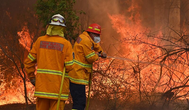 Firefighters tackle a bushfire to save a home in Taree, 350km north of Sydney as they try to contain dozens of out-of-control blazes that are raging in the state of New South Wales.  AFP