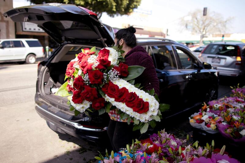 A woman lifts a funeral display into a car in the flower district as the coronavirus disease (COVID-19) outbreak continues, ahead of Valentine's Day in Los Angeles, California, U.S. Reuters