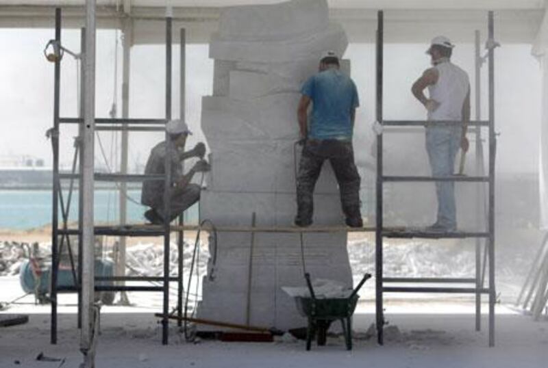 With the Arabian Gulf in the background, Husam Chaya, right, supervises assistants as his piece takes shape at the Armed Forces Officers Club.