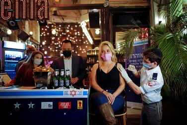 A woman receives a vaccination shot against the coronavirus disease as part of a Tel Aviv municipality initiative offering a free drink at a bar to residents getting the shot, in Tel Aviv, Israel on February 18, 2021. Reuters