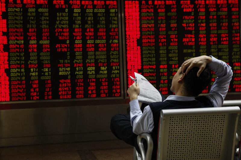 An investor with a newspaper looks at stock market data displayed on an electronic board at a securities brokerage house in Beijing, China. EPA