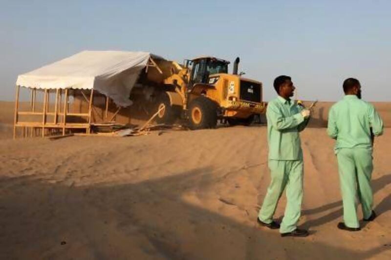 Workers from Dubai Municipality demolish the unregistered winter camps in the Al Mushrif area of Dubai yesterday. More will be torn down today unless owners get them registered immediately.
