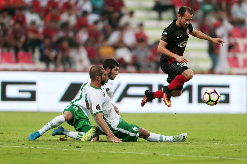 Al Ahli’s Everton Ribeiro, right, controls the ball while jumping over Emirates’ Alhassan Saleh, bottom left, and Hadef Saif, bottom right. Christopher Pike / The National