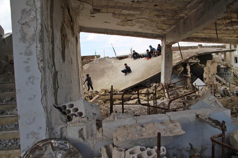 Syrian children slide on the collapsed roof of a school which was hit by bombardment in the district of Jisr al-Shughur, in the west of the mostly rebel-held Idlib province, on January 30, 2019.  / AFP / Ibrahim YASOUF
