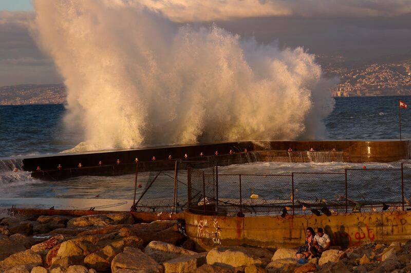 A couple drinks coffee as waves smash along the Beirut coastline, Lebanon. AP Photo