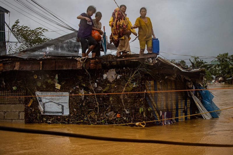 RODRIGUEZ, PHILIPPINES - NOVEMBER 12: Stranded residents wait to be rescued atop a roof as floodwaters continue to rise in a village, as Typhoon Vamco hits on November 12, 2020 in Rodriguez, Rizal province, Philippines. Typhoon Vamco has battered the Philippines causing widespread flooding and destruction in areas still reeling from the effects of Super Typhoon Goni. Authorities on Thursday have mounted several rescue operations as tens of thousands of homes have been submerged in floodwaters. Flights and mass transit in Manila were suspended, as well as work in government offices. (Photo by Ezra Acayan/Getty Images)