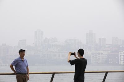 A tourist poses for a photograph as commercial and residential buildings stand shrouded in haze in Sydney, New South Wales, Australia, on Wednesday, Jan. 8, 2020. As Sydney faced another day of toxic haze shrouding the skyline, U.S. weather satellite captured the smoke crossing South America and spreading out over Buenos Aires before it drifted into the Atlantic Ocean -- some 7,328 miles (11,793 kilometers) east of Sydney -- according to the National Oceanic and Atmospheric Administration. Photographer: Brent Lewin/Bloomberg