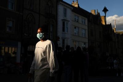 A woman wearing a face mask or covering due to the COVID-19 pandemic, walks in the evening sunshine in Durham, northeast England on September 29, 2020, after tighter restrictions were put in place to help mitigate the spread of COVID-19.  More than two million people in northeast England face new restrictions because of a surge in coronavirus cases, the government announced on Thursday, as it battled to contain a potential second wave of infection. Tighter regulations on socialising are due to come into force from Friday in Northumberland, North and South Tyneside, Newcastle-upon-Tyne, Gateshead, and County Durham. Residents will be banned from socialising in homes or gardens with people from outside their household, while food and drink venues will be restricted to table service only. / AFP / Oli SCARFF
