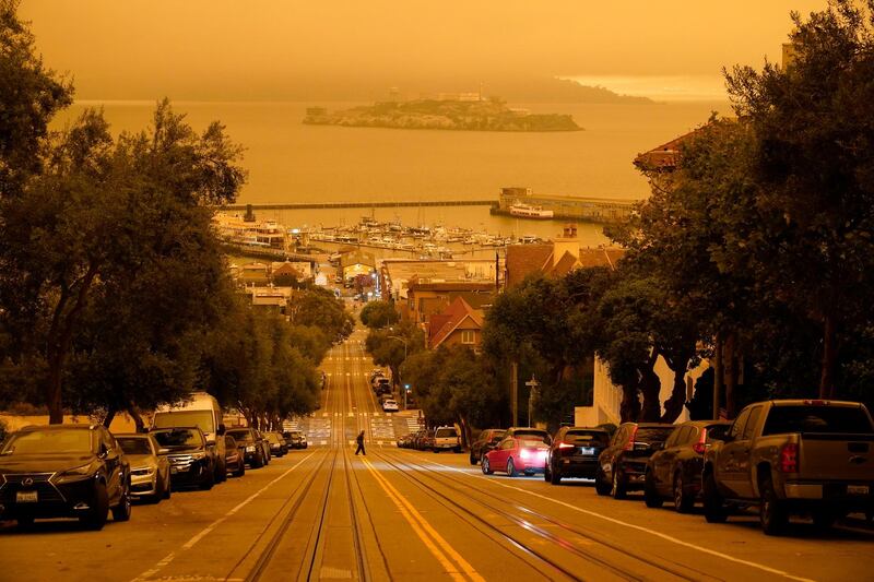 Under darkened skies from wildfire smoke, a man crosses Hyde Street with Alcatraz Island and Fisherman's Wharf in the background, in San Francisco. AP Photo