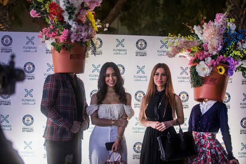 Visitors pose alongside people sporting floral headgear for a celebratory vibe at the venue.