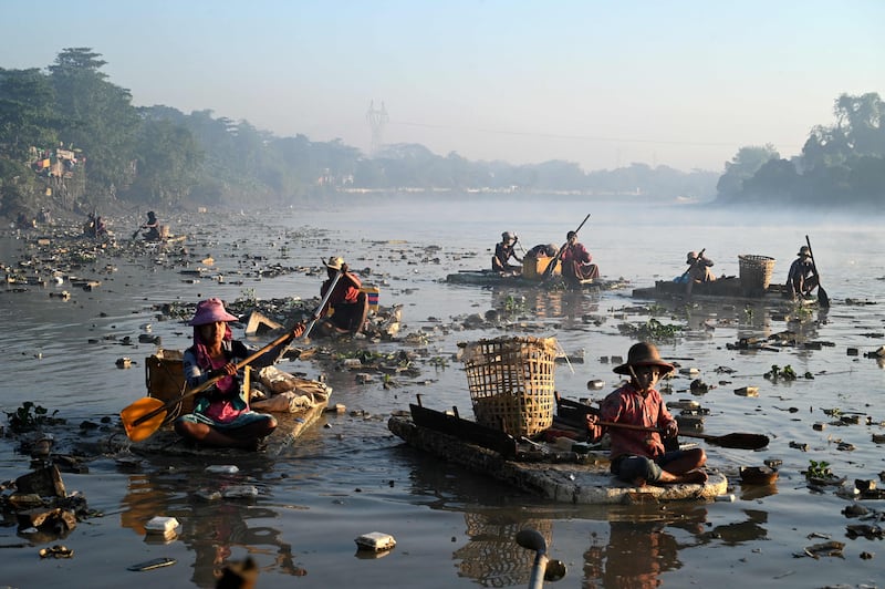 Waste collectors paddle polystyrene boats as they look for plastic and glass to recycle in a creek in Yangon, Myanmar.  AFP
