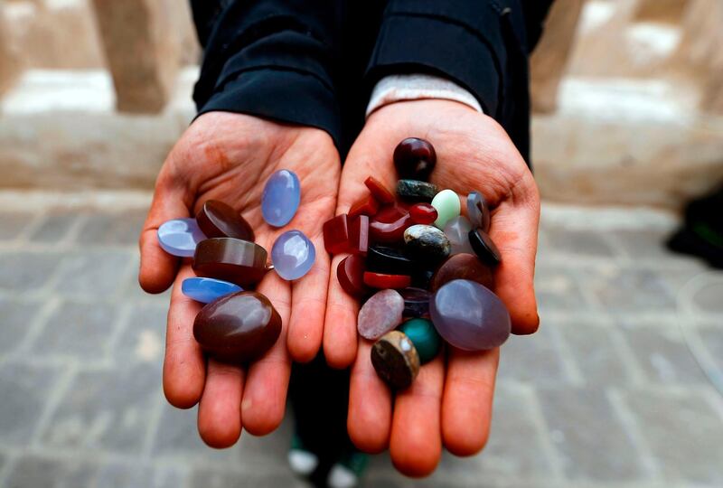 Safa al-Faqih, one of the few female Yemeni craftsmen working in the precious stones industry in Yemen, holds precious stones in the old city of the capital, Sanaa, on April 18, 2018. Due to the ongoing war in Yemen just a quarter of artisans are still working in Sanaa's old market, where the majority of gemstones were sold, and the men who previously dominated the industry have mostly gone in search of other work. Mohammed Huwais / AFP Photo