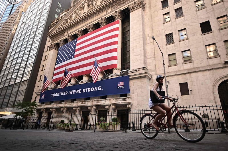A woman rides past the New York Stock Exchange (NYSE) on July 13, 2020 at Wall Street in New York City. / AFP / Johannes EISELE
