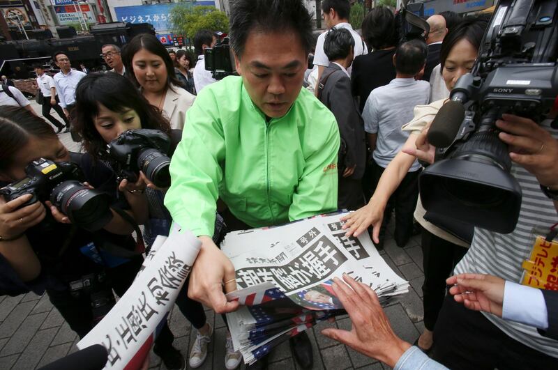 A staff member of a Japanese newspaper Yomiuri distributes an extra edition of the newspaper reporting about the summit at Shimbashi Station in Tokyo. Koji Sasahara / AP Photo