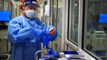 A nurse puts on PPE in a ward for Covid patients. PA