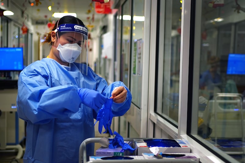 A nurse puts on PPE in a ward for Covid patients. PA