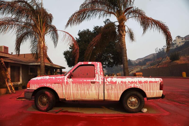 A vehicle and driveway are covered in fire retardant after it was sprayed from a firefighting aircraft as the Holy Fire burns nearby in Lake Elsinore, California. AFP