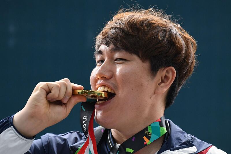 South Korea's Jeong You-jin bites into his gold medal after winning the 10m men's shooting. Mohd Rasfan / AFP