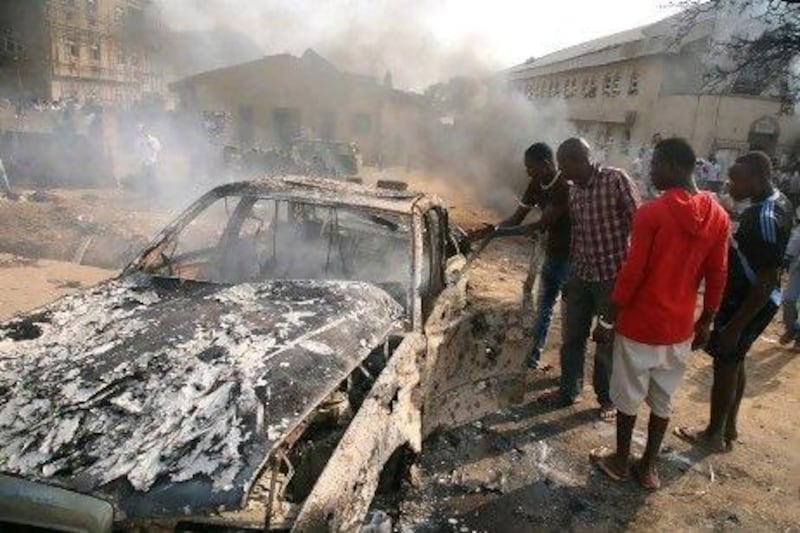 Men look at the wreckage of a car following a bomb blast in the Nigerian capital Abuja on December 25. Boko Haram, a militant group in the country, with affiliations to Al Qaeda, claimed responsibility.