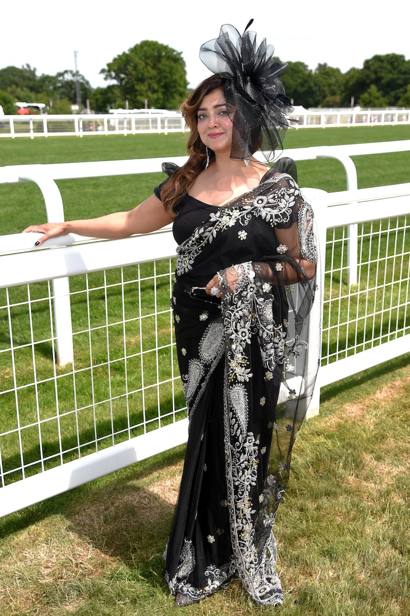 An attendee in a black sari with matching fascinator. 
