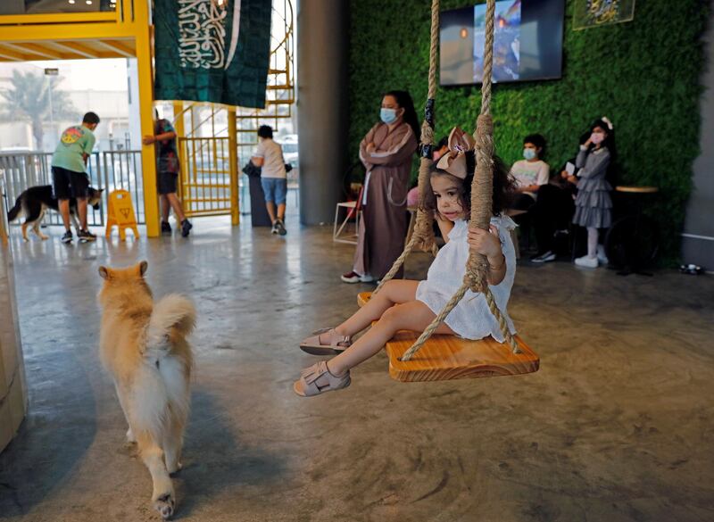 A child swings as dogs are seen at "Barking Lot" cafe where customers can bring their dogs in Khobar, Saudi Arabia. Reuters