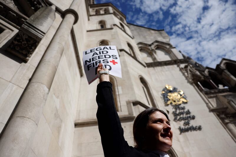 A lawyer holds a placard outside the Royal Courts of Justice in London, as they go on strike in a dispute over pay. AFP