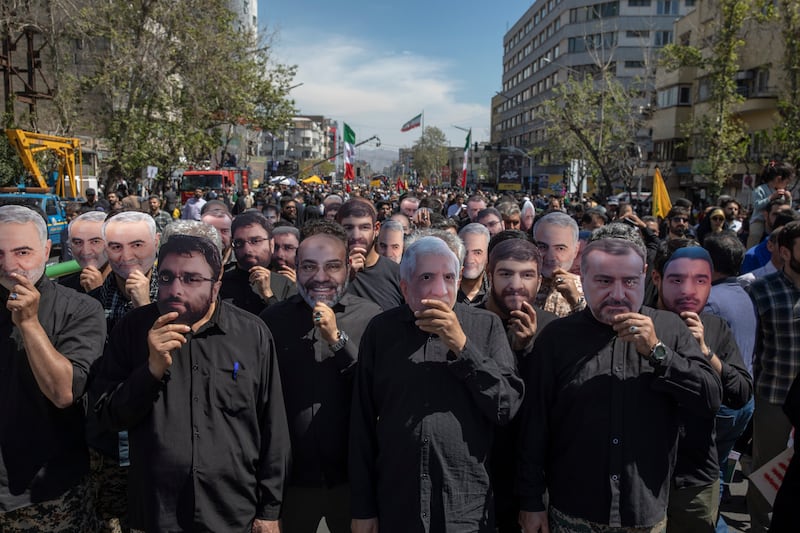 Iranians wearing masks of the dead in the funeral procession for the seven Islamic Revolutionary Guard Corps members killed, in Tehran. Getty Images