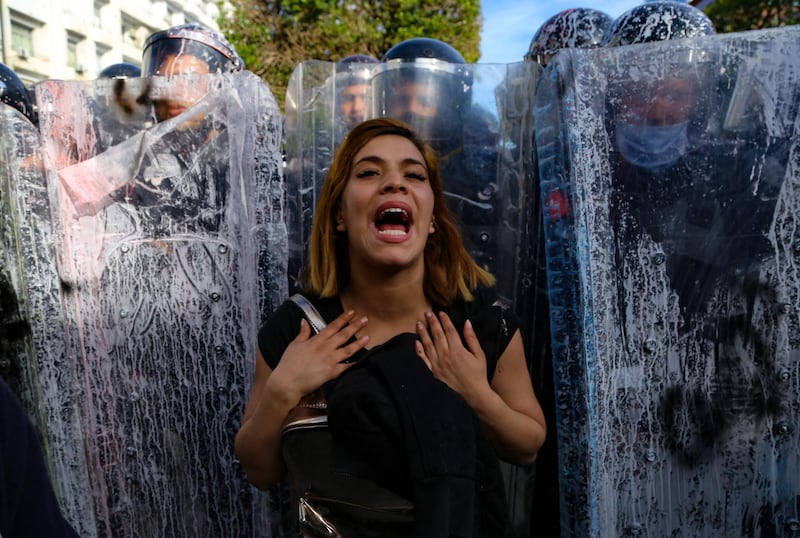 A Tunisian woman reacts as she stand in front of police officers forming a human shield. AFP