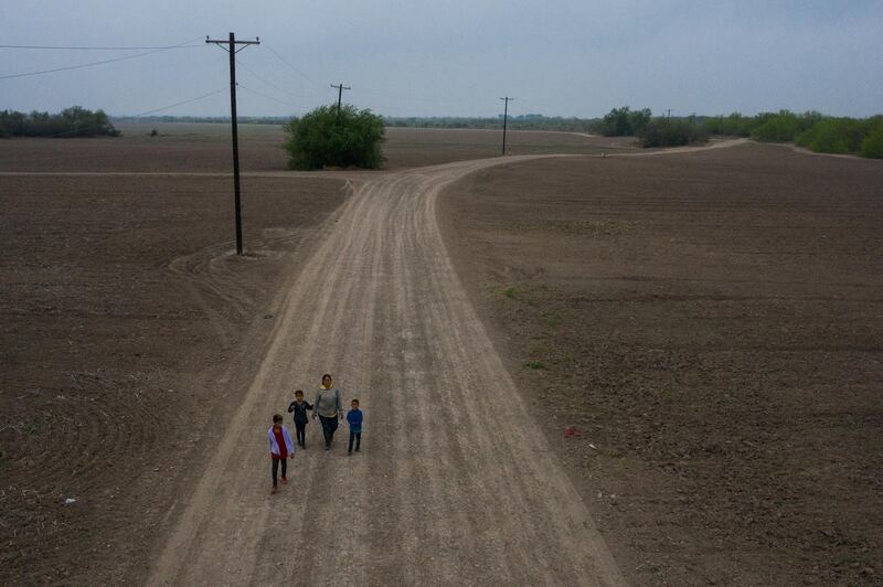 Sonia, a migrant from Honduras, walks down a dirt road with her children Jefferson, 9, Scarlet, 7, and David, 6, after they crossed the Rio Grande into the US from Mexico on a raft, in Penitas, Texas.  Reuters