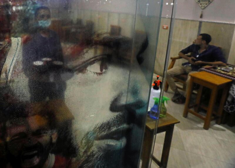A man stands behind a screen depicting Liverpool player Mohamed Salah at a cafe, after months of lockdown, in Cairo, Egypt. Reuters