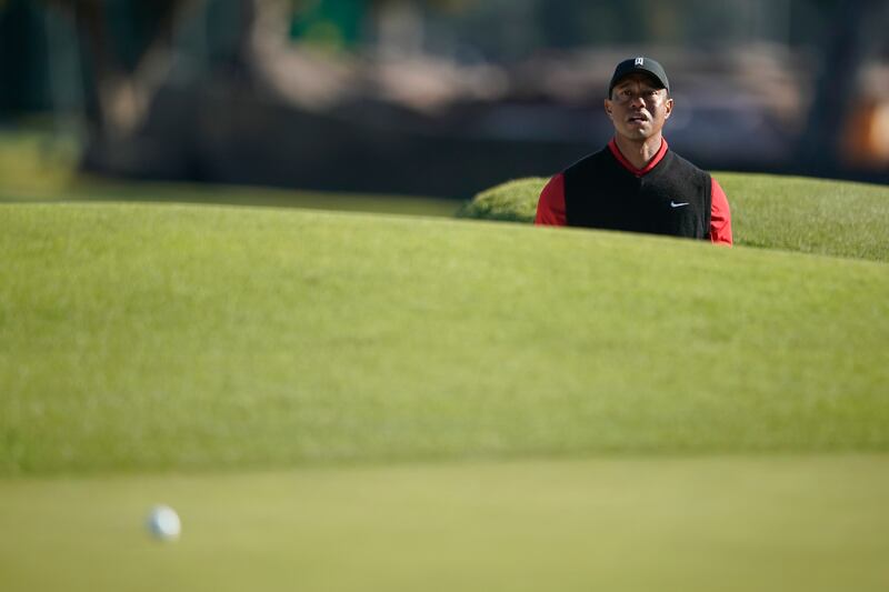 Tiger Woods watches his shot after hitting out of a bunker on the third hole. EPA