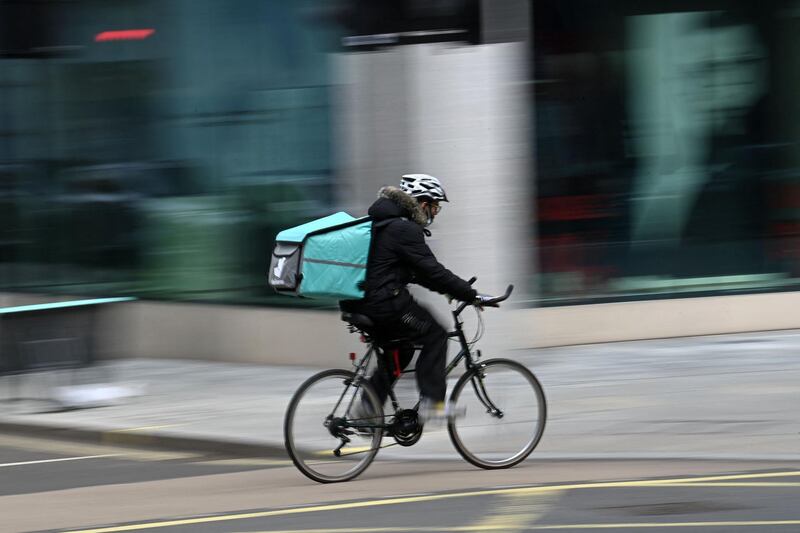 A Deliveroo rider cycles through central London on March 26, 2021. The meal delivery platform Deliveroo is bracing for strikes and other social actions by disgruntled riders as it gears up for a major London stock listing.  The group has come under fire for employment conditions that have already scared off a couple of large institutional investors
 / AFP / DANIEL LEAL-OLIVAS
