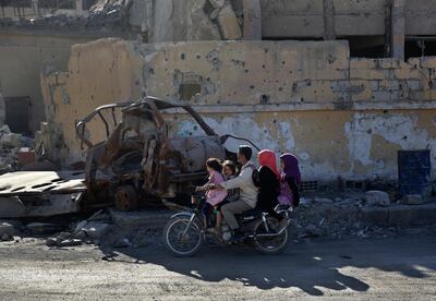 In this Thursday, April 5, 2018 photo, a family rides a motorcycle on a street that was  damaged during fighting between U.S.-backed Syrian Democratic Forces fighters and Islamic State militants, in Raqqa, Syria. Six months after IS was driven out, residents of Raqqa feel they have been abandoned as the world moves on. They are trying to rebuild but fear everyone around them: the Kurdish-led militia that administers the majority Arab city; Syrian government forces nearby; gangs who kidnap or rob whoever shows signs of having money; and IS militants who may still be hiding among the people. (AP Photo/Hussein Malla)