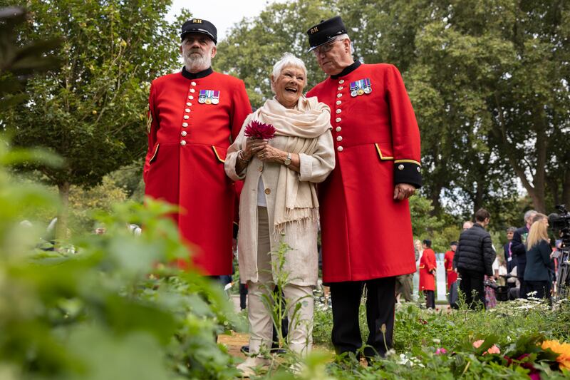 Dame Judi Dench stands with Chelsea pensioners on the RHS Queen's Green Canopy Garden. Getty Images